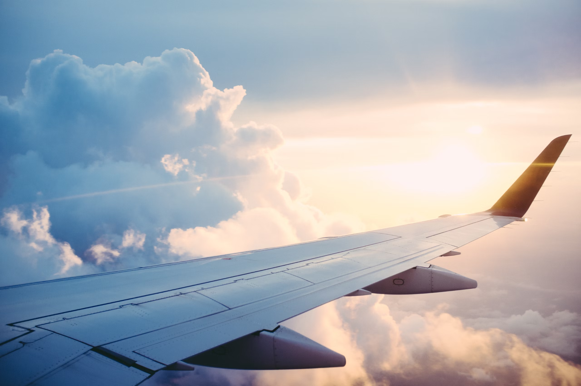 Airplane wing with clouds at sunset
